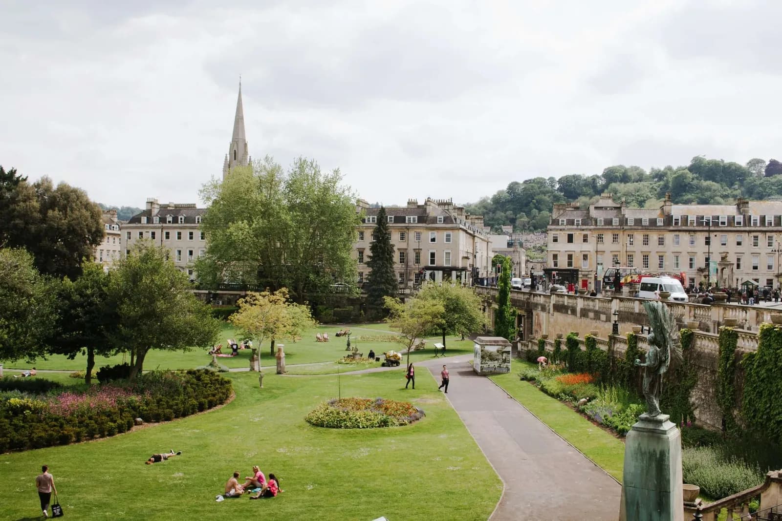 Parade Gardens in Bath, people on the lawn below the Georgian terraces with a church spire behind