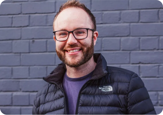 chris, the founder of bristechtonic, smiling against a charcoal brick background