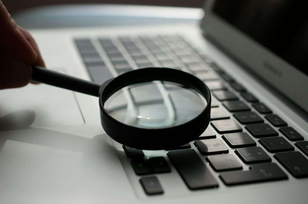 Magnifying glass on a laptop keyboard, representing search engine queries