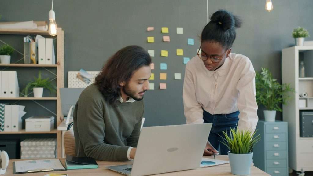Two colleagues collaborating on a project at a desk.
