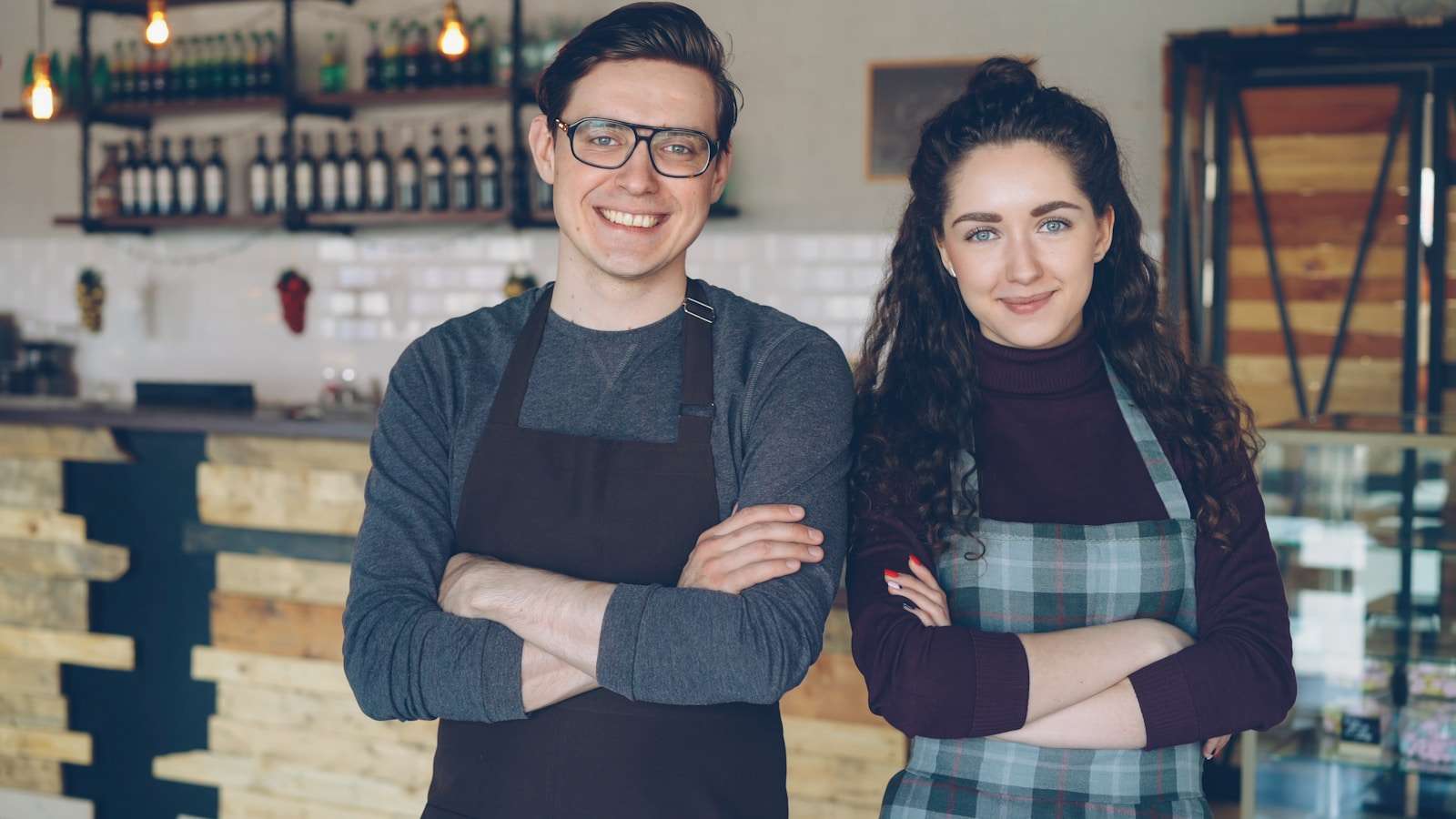 Two small business owners standing in the doorway of their cafe